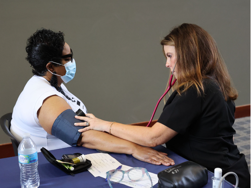 nurse educator performs a manual blood pressure check during a health screening
